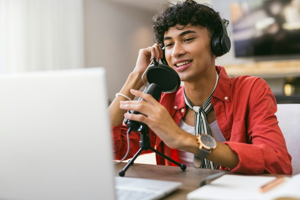 Recording podcast, teenage boy using microphone and laptop at home