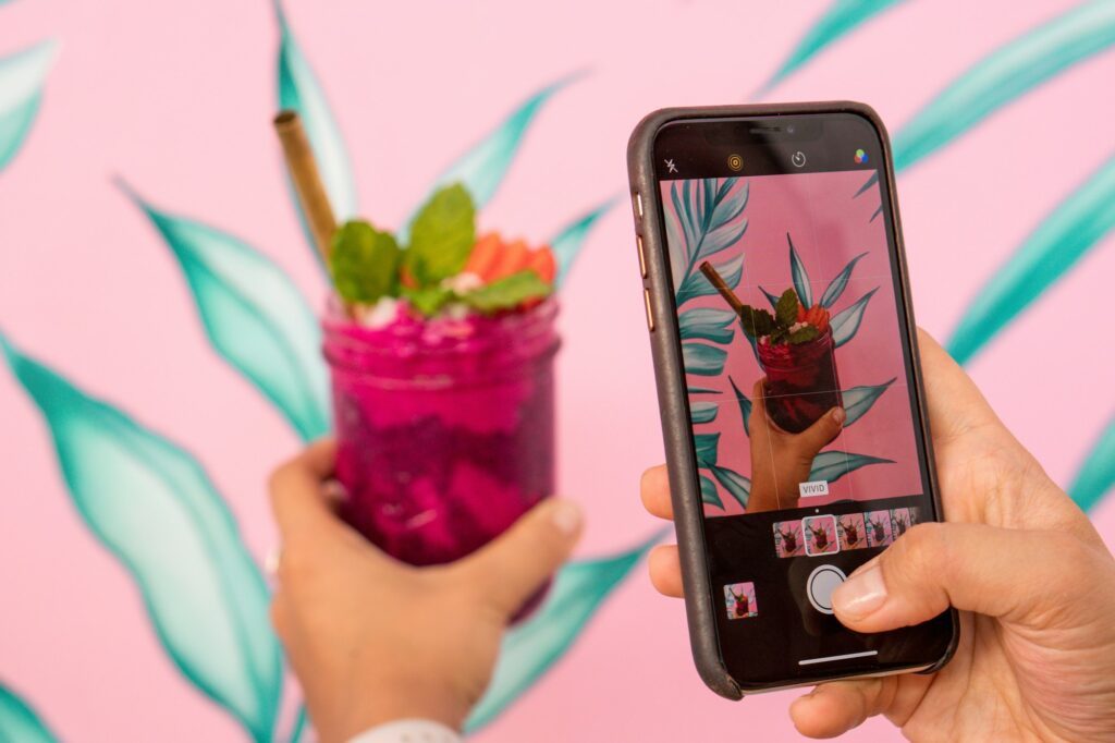 Woman taking photo of the colorful smoothie on her mobile phone